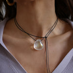 A person wearing a angel aura quartz stone necklace with an adjustable black cord.