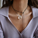 A person wearing a angel aura quartz stone necklace with an adjustable black cord.