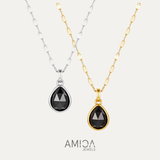 Two black teardrop pendants on gold and silver chains with AMICA Jewels branding.