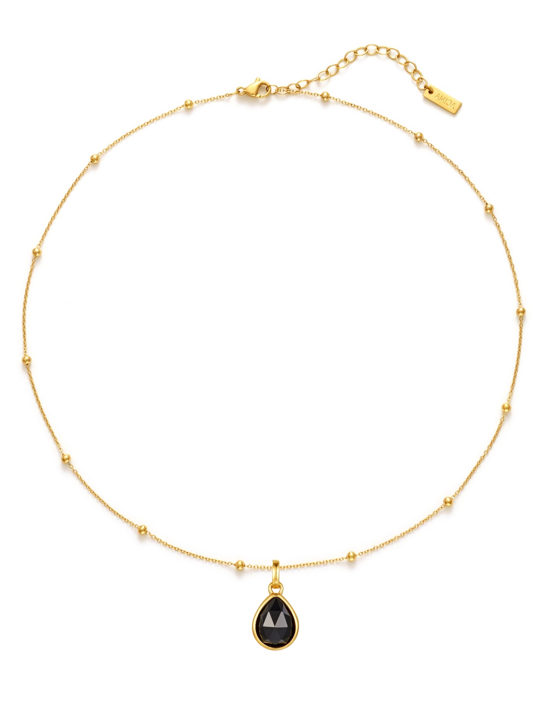 Gold necklace with a black teardrop pendant on a white background