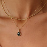 Gold necklace with a black pendant on a person's neck