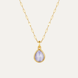 Gold necklace with a teardrop-shaped purple gemstone pendant on a light gray background