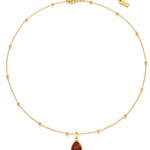 Gold necklace with a red teardrop pendant on a white background