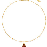 Gold necklace with a red teardrop pendant on a white background