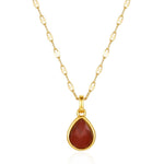 Gold necklace with a red teardrop pendant on a white background