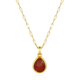 Gold necklace with a red teardrop pendant on a white background