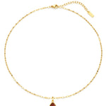 Gold necklace with a red teardrop pendant on a white background
