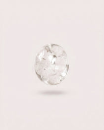 Polished Clear Quartz donut gemstone charm on a light background
