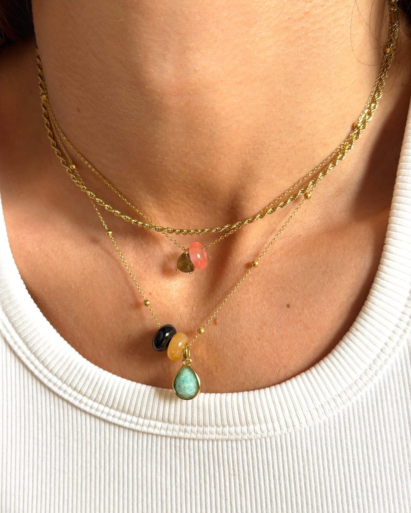 Layered gold necklace with colorful gemstone charms and a green teardrop pendant