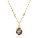 Gold necklace with a teardrop-shaped gemstone pendant on a white background