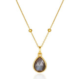 Gold necklace with a teardrop-shaped gemstone pendant on a white background