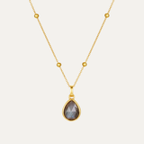 Gold necklace with a teardrop-shaped pendant on a light gray background