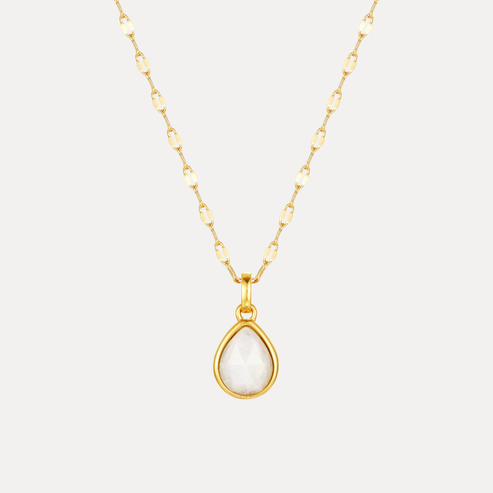 Gold necklace with a teardrop-shaped pendant on a light gray background