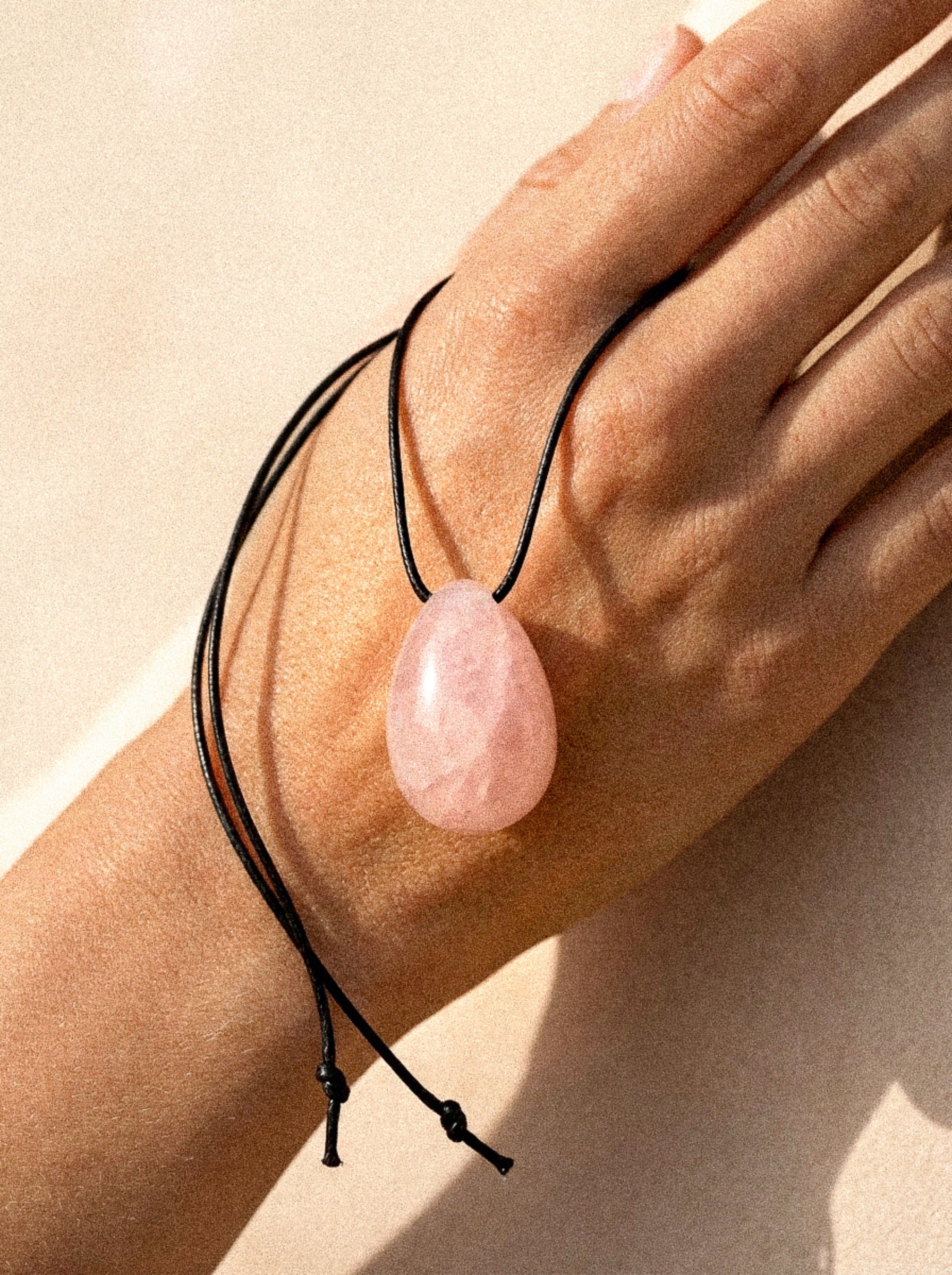 Rose Quartz pendant necklace resting on a model hand