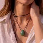 Close-up of model adjusting a Green Aventurine pendant necklace