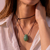 Close-up of model adjusting a Green Aventurine pendant necklace
