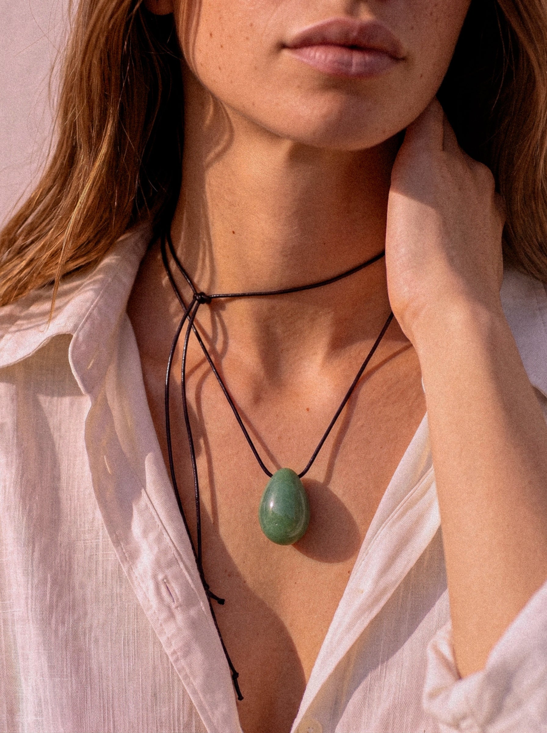Close-up of model adjusting a Green Aventurine pendant necklace