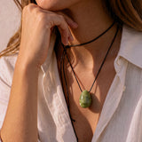 Model wearing a green jade egg-shaped pendant on a long black silk cord