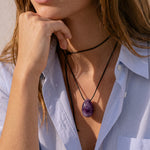 Close-up of model wearing an Amethyst pendant with hand at chin