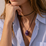 Close-up of model wearing an Amethyst pendant with hand at chin