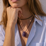 Model wearing a long Amethyst pendant necklace over a blue shirt
