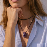 Model wearing a long Amethyst pendant necklace over a blue shirt