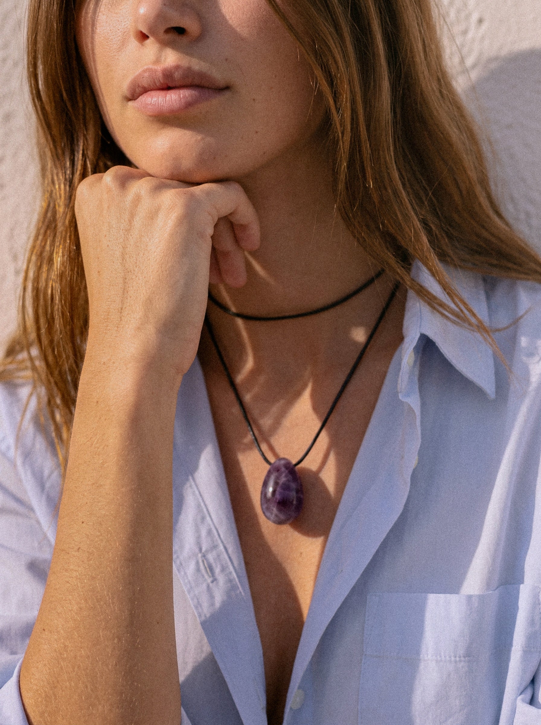 Model wearing a long Amethyst pendant necklace over a blue shirt