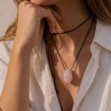 Model wearing a long Rose Quartz pendant necklace over a white shirt