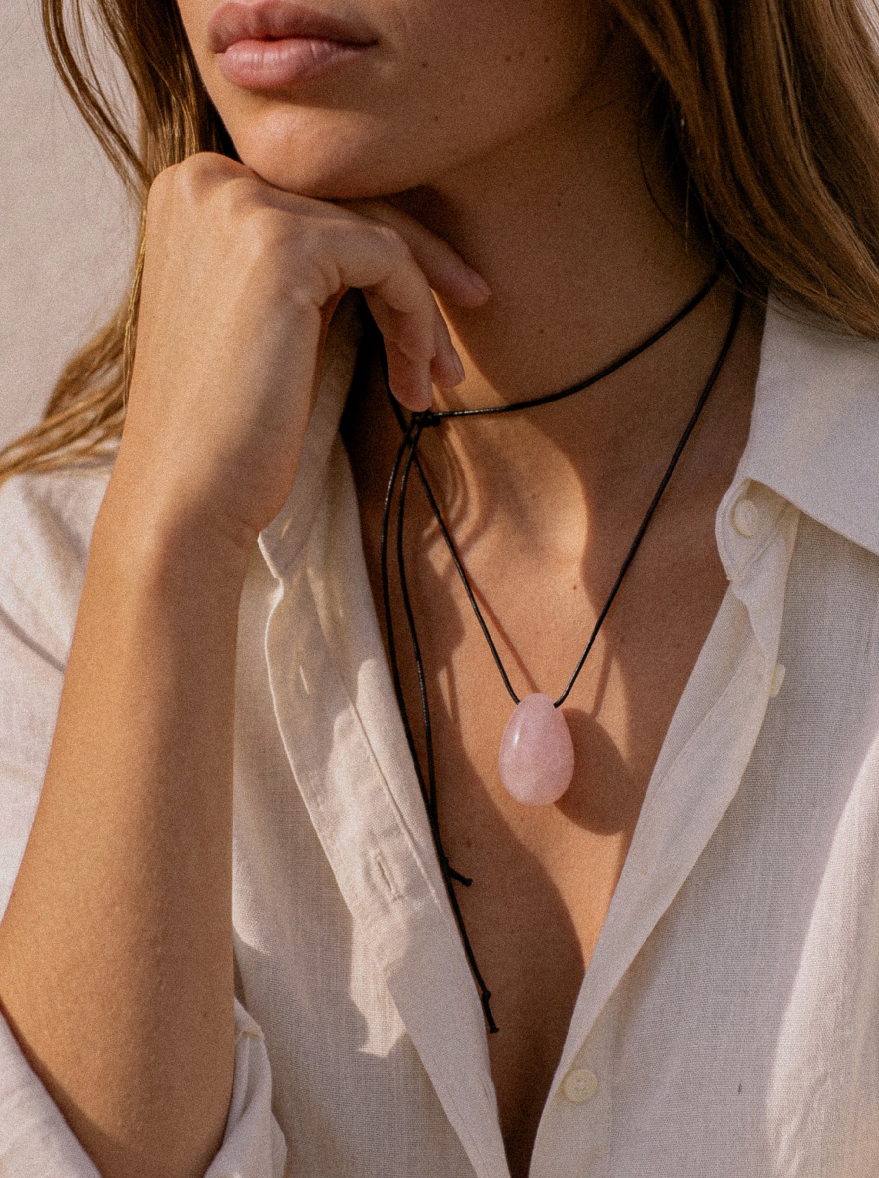Model wearing a long Rose Quartz pendant necklace over a white shirt