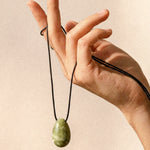 Light green Jade pendant and adjustable black silk cord displayed by hand