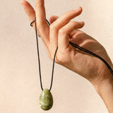 Light green Jade pendant and adjustable black silk cord displayed by hand