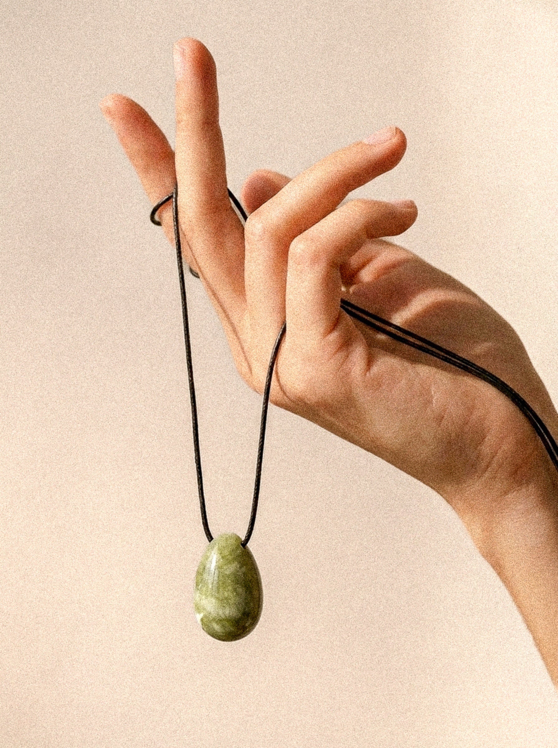 Light green Jade pendant and adjustable black silk cord displayed by hand