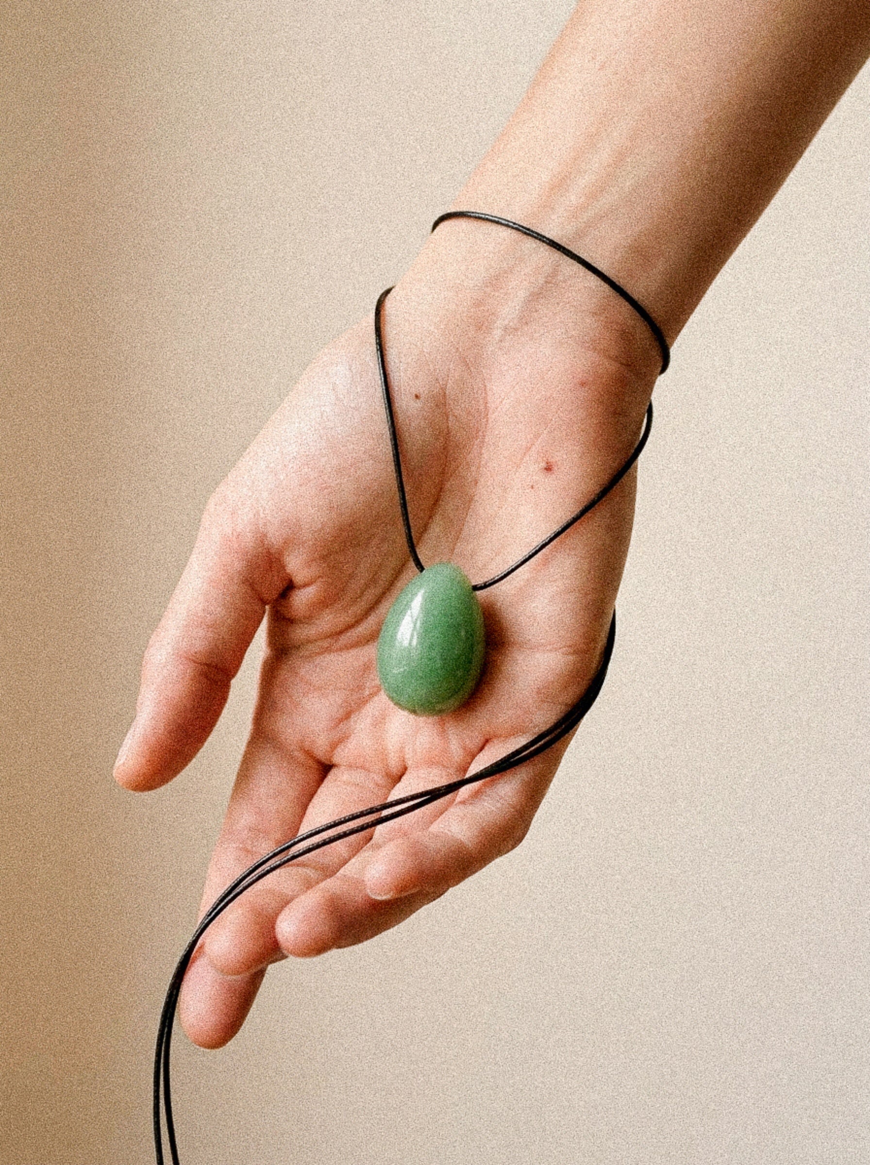 Green Aventurine egg-shaped pendant necklace displayed in an open hand