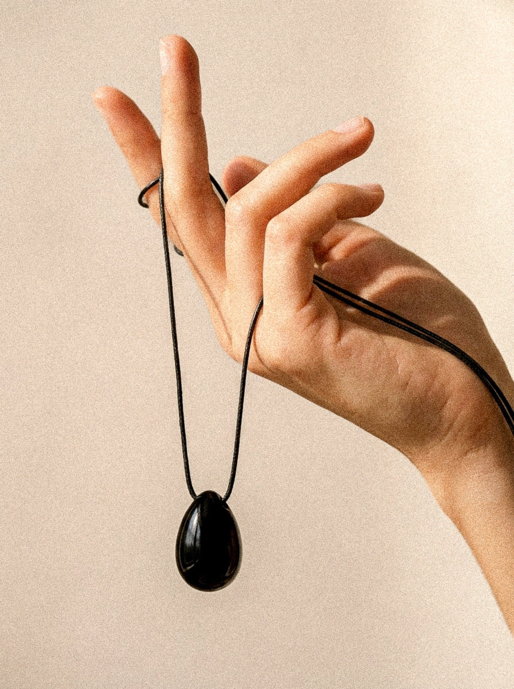 Black Obsidian pendant and long adjustable black cord displayed by hand