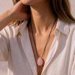 Model wearing a Rose Quartz pendant with layered black cord styling