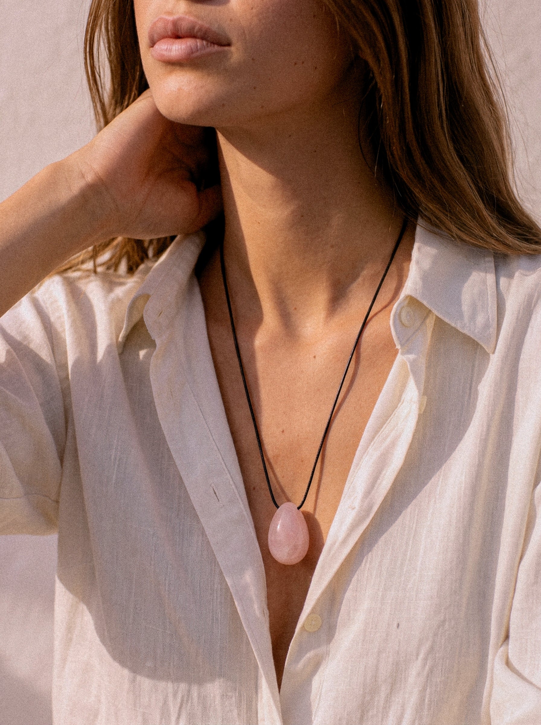 Model wearing a Rose Quartz pendant with layered black cord styling