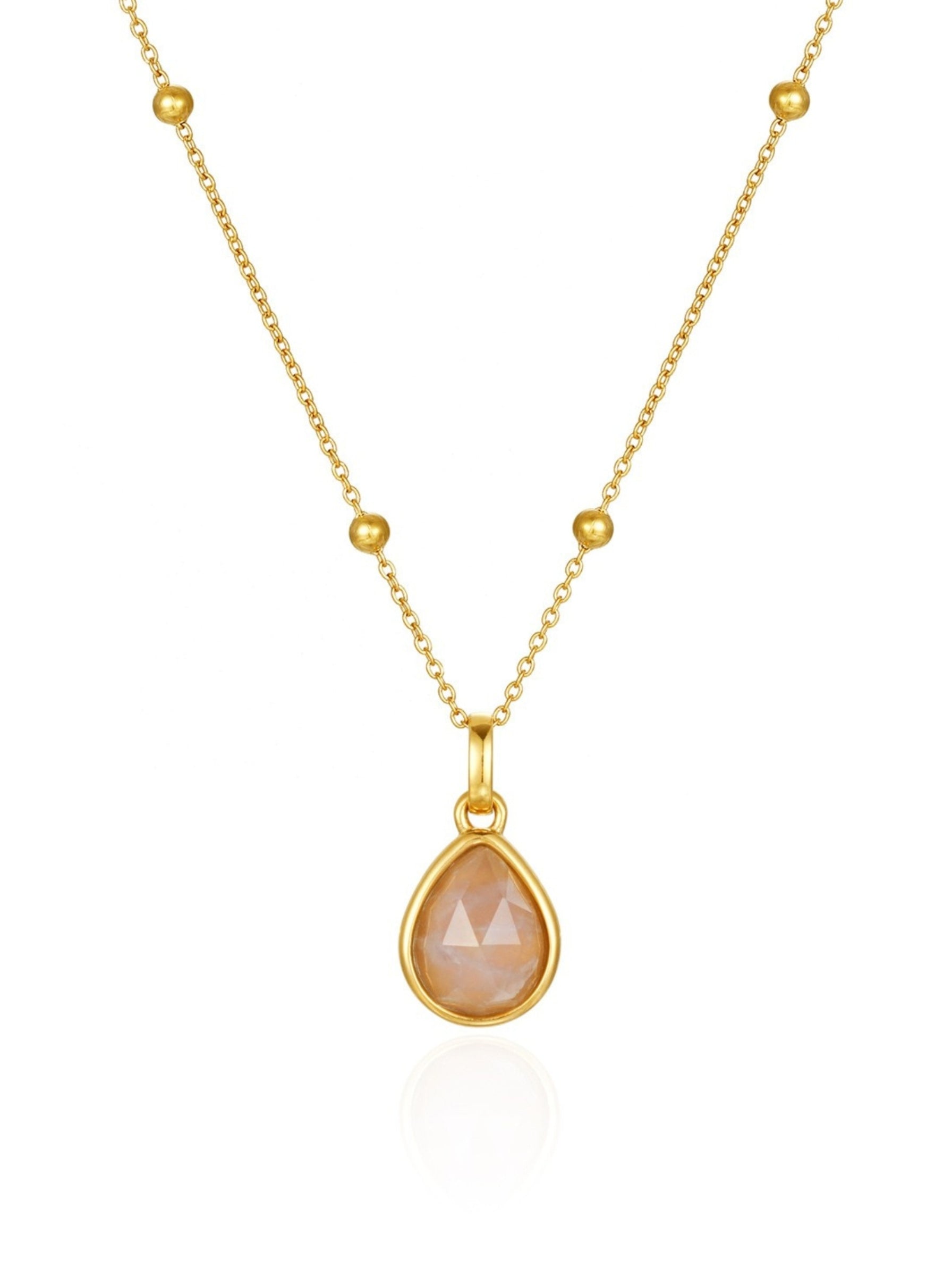 Gold necklace with a teardrop-shaped peach-colored gemstone on a white background