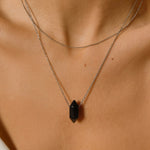 Black obsidian crystal necklace. The necklace features a pointed black obsidian crystal pendant attached to a gold chain, creating a stunning and eye-catching piece of jewelry.