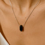 Black obsidian crystal necklace. The necklace features a pointed black obsidian crystal pendant attached to a gold chain, creating a stunning and eye-catching piece of jewelry.
