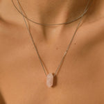 Rose Quartz crystal necklace. The first necklace features a pointed rose quartz crystal pendant, while the second necklace features a delicate gold snake chain. Together, the necklaces create a stunning layered look that adds sophistication and elegance to any outfit.