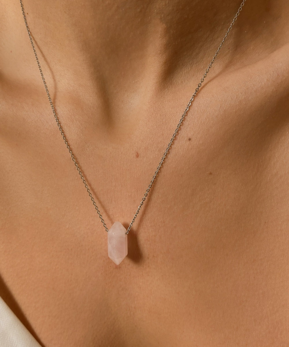 Rose Quartz crystal necklace. The first necklace features a pointed rose quartz crystal pendant, while the second necklace features a delicate gold snake chain. Together, the necklaces create a stunning layered look that adds sophistication and elegance to any outfit.