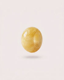 Polished Yellow Jade donut gemstone charm on a light background